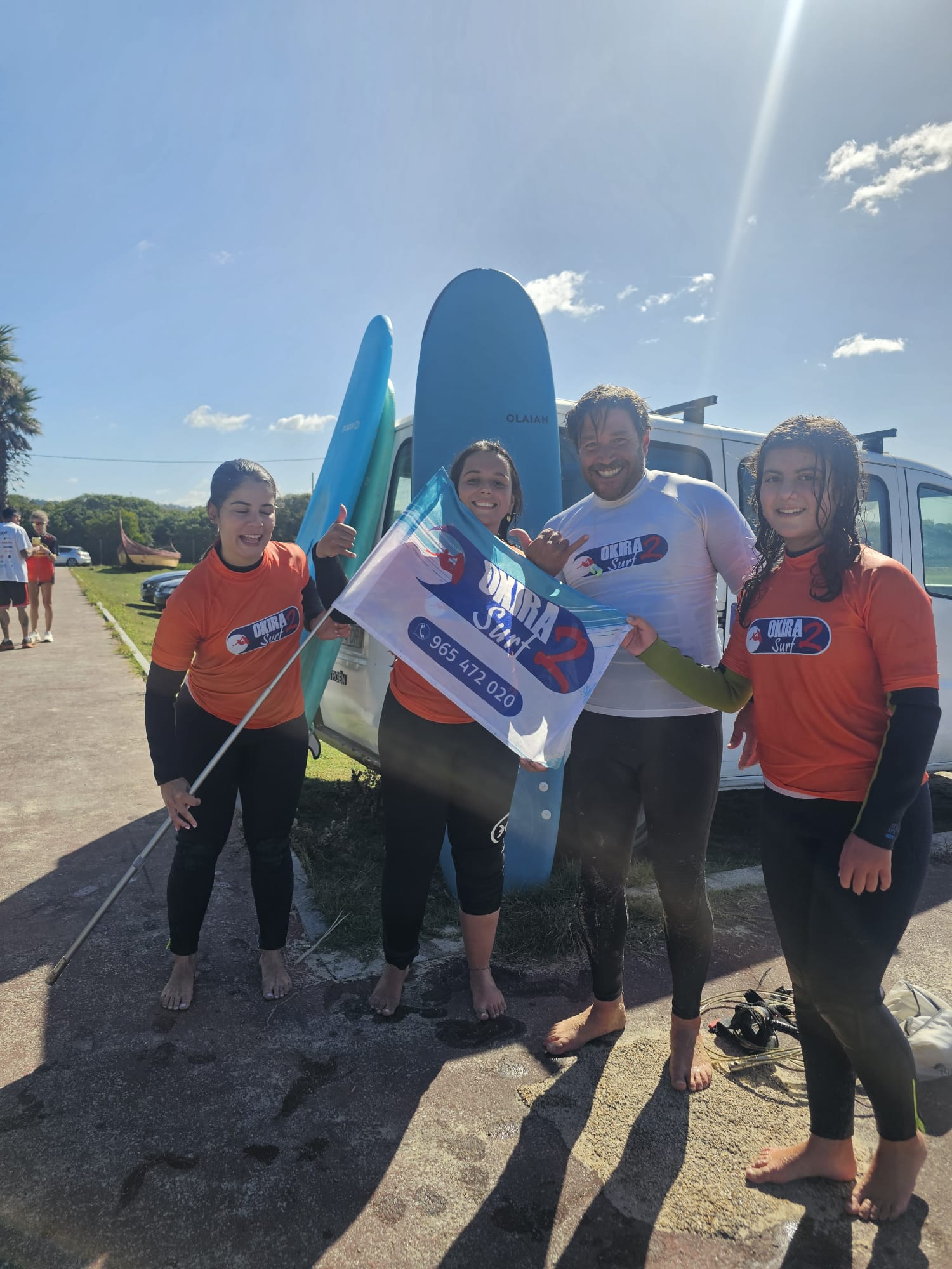 Okira Surf team with boards and school flag — surf lessons near Porto and Praia da Aguda